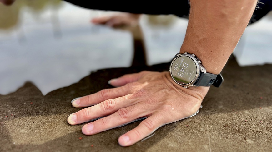 Chytré hodinky Garmin fēnix® 9 Pro na zápěstí muže, který právě provádí kliky na betonové ploše skropené deštěm