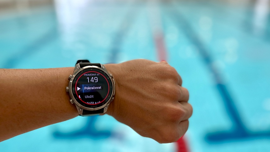 Chytré hodinky Garmin fēnix® 9 Pro v detailu na zápěstí v popředí plaveckého bazénu