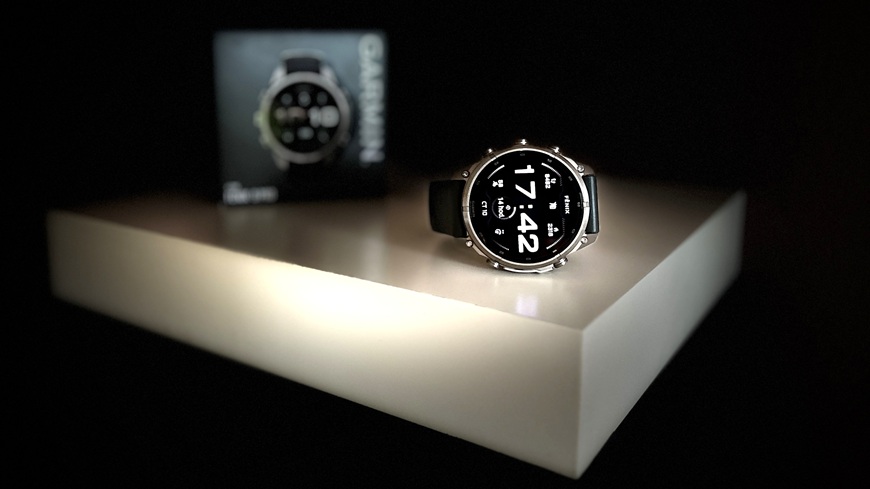 Chytré hodinky Garmin fēnix® 9 Pro v detailu s krabičkou na spoře osvětlené poličce