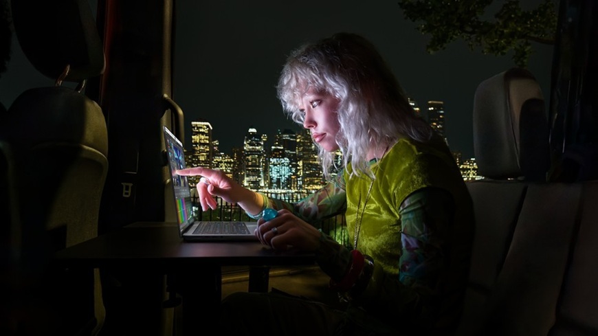 Láska na první PROLED! Apple do třetice všeho nového představil první dotykový MacBook Pro Mladá blonďatá žena dotýkající se prstem PROLED displeje MacBooku Pro