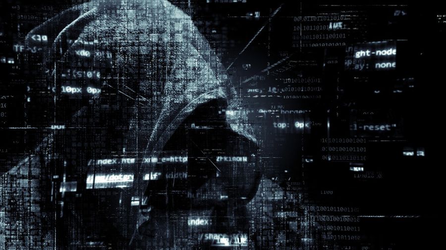 obrázek ilustrující představu hackera, muže v kapuci za počítačem