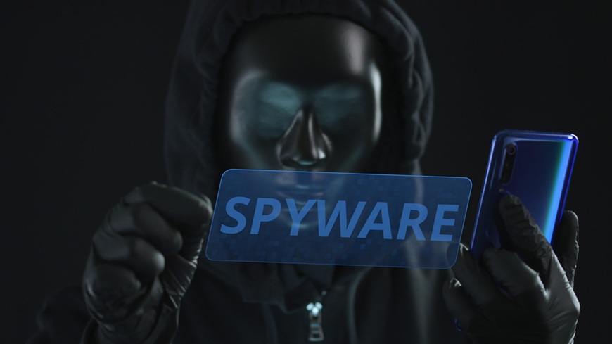 nápis spyware a muž s mobilem a maskou