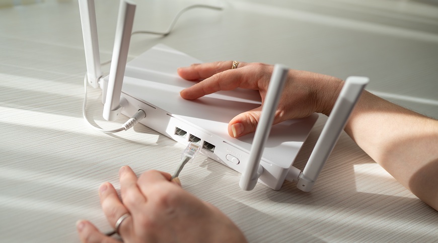 Jak připojit notebook k internetu? Žena zapojuje ethernetový kabel k routeru