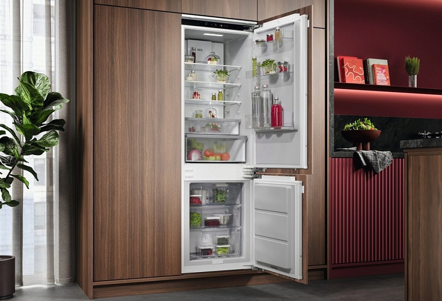 27 dB ticha: Lednice AEG přináší nový standard chlazení Otevřená lednice AEG v kuchyni s dřevěným dekorem.