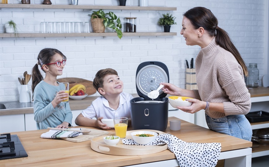 žena a děti vaří rýži v rýžovaru v moderní kuchyni