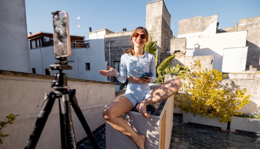 Žena natáčí videa na mobilní telefon se stativem