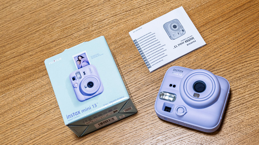 Recenze: Fujifilm instax Mini 13 – Instantní fotoaparát, který promění vzpomínky ve skutečné fotografie krabička od instaxu, příbalový leták a fialový instax Mini 13