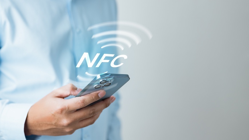 Jak platit mobilním telefonem? Muž drží v ruce mobilní telefon, nad kterým je symbolNFC.