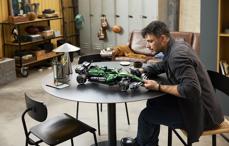 Muž staví u stolu stavebnici LEGO - formule LEGO Technic.