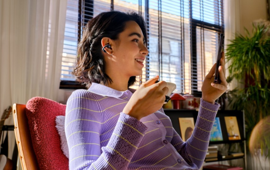 Shokz OpenDots 2 a OpenDots Air: Otevřená sluchátka, která vás neodříznou od okolí Žena má sluchátka OpenDots Air a sleduje video na svém mobilním telefonu